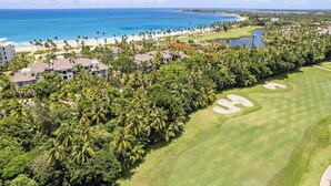 A golf course with a water hazard, surrounded by lush greenery and a beach.