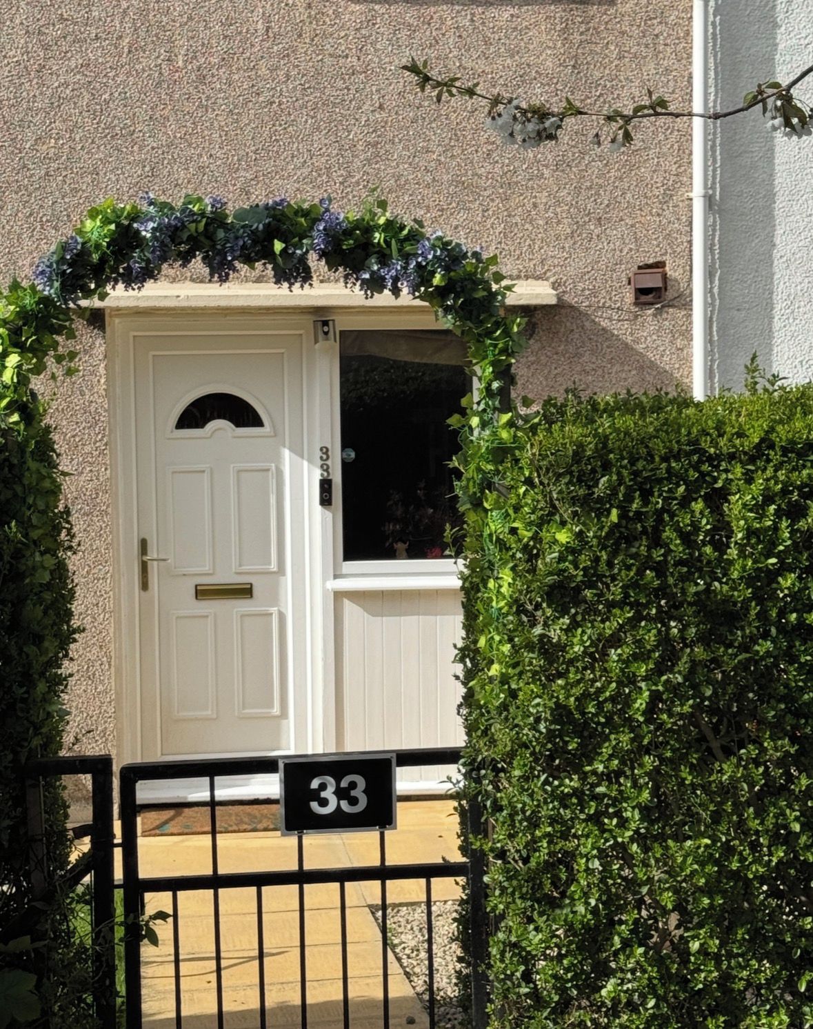 A white door with a number '33' sign, a small window, and a black metal gate.