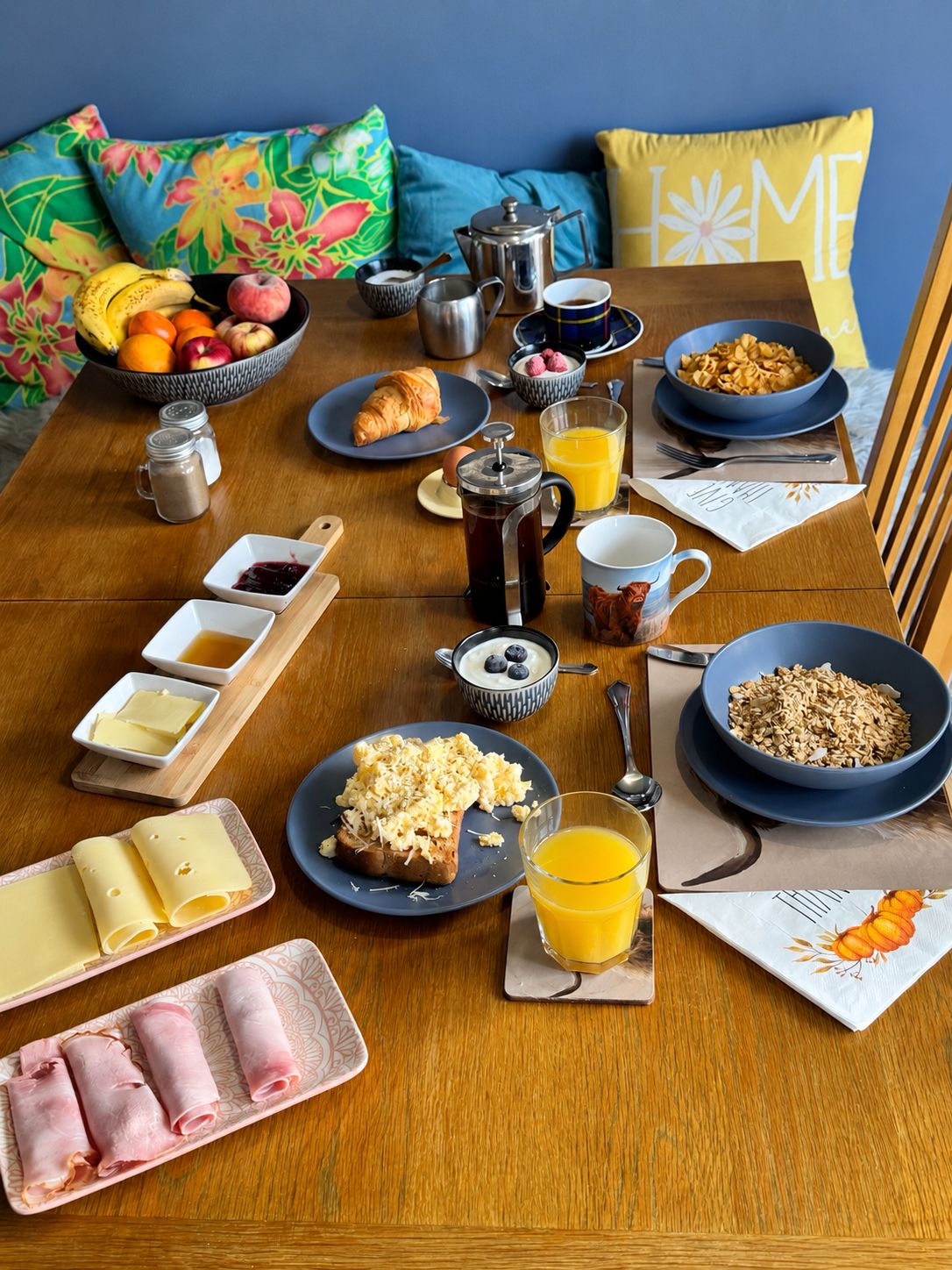 Una mesa de desayuno dispuesta con diversos platos, entre ellos frutas, huevos y bebidas.