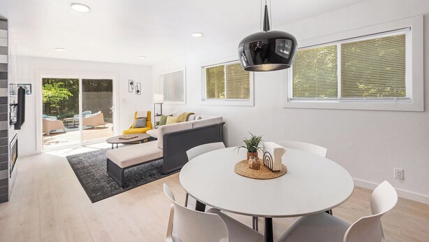 A modern living room with a dining area, large windows, and a kitchen visible in the background. - 3 Bedroom, 1.5 Bath Chalet minutes from Hamlin Lake. Sleeps 8 (Ludington)