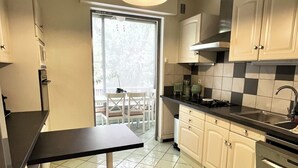 A modern kitchen with white cabinets, a black countertop, and a window overlooking a balcony. - La Casa de la Rosa (Mandelieu-la-Napoule)