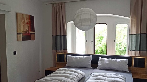 A bedroom with a large bed, wooden headboard, and a hanging light fixture.