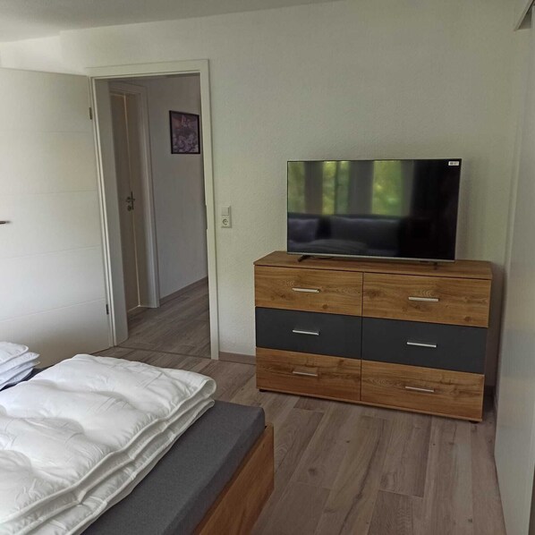 Un dormitorio con una cama, un aparador de madera y un televisor.