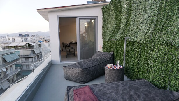 A rooftop terrace with two grey cushioned seating areas, a small round table, and a sliding glass door leading to an indoor space. - LOFT WITH PRIVATE TERRACE AND PARTHENON VIEWS (Athina)