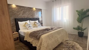Ein modernes Schlafzimmer mit Bett, Nachttisch und einer Topfpflanze.