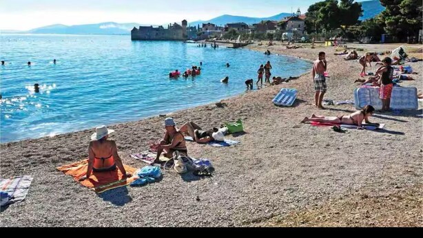 Ein Strand mit Personen, die sich sonnen und schwimmen.