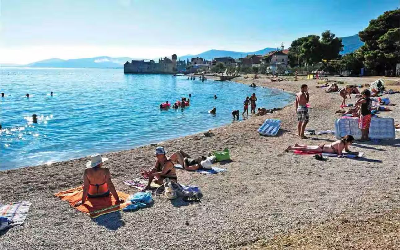 A beach with people sunbathing and swimming.