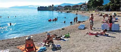 A beach with people sunbathing and swimming.