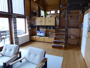 A wooden interior with a TV, seating, and a staircase.