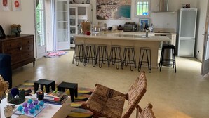 A spacious living area with a kitchen, a dining area with bar stools, and a large window with a view of the outdoors. - CHARMING CORSICAN HOUSE (Barbaggio)