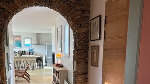 A hallway with a stone archway leading to a kitchen area. - CHARMING CORSICAN HOUSE (Barbaggio)