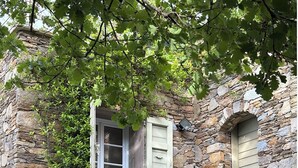 A stone building with a window and a door, surrounded by greenery. - CHARMING CORSICAN HOUSE (Barbaggio)