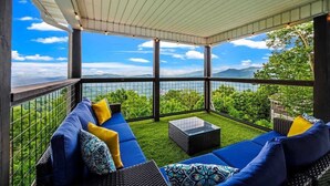A covered outdoor seating area with a view of mountains and greenery.