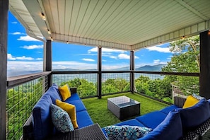 A covered outdoor seating area with a view of mountains and greenery. - Heaven's Peak: VIEWS,HotTub,Sauna,Jacuzzi,Arcade (Gatlinburg)