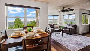 A dining area with a table set for four, a leather sofa, and a ceiling fan.