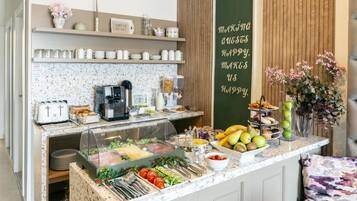 A breakfast bar with a coffee machine, a variety of food items, and a sign that reads "Making Guests Happy Makes Us Happy."