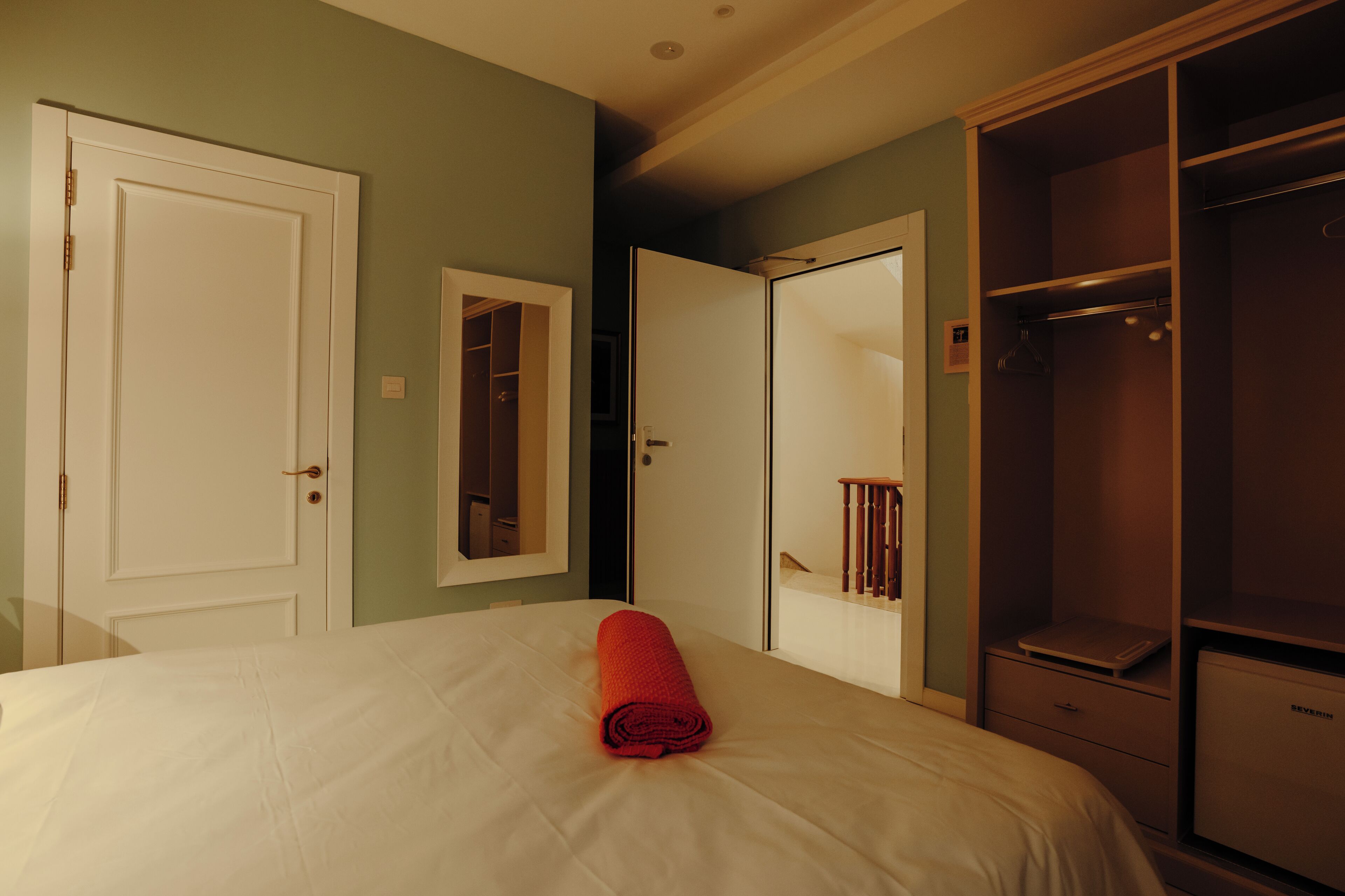 A hotel room with a bed, a wardrobe, and a mirror.