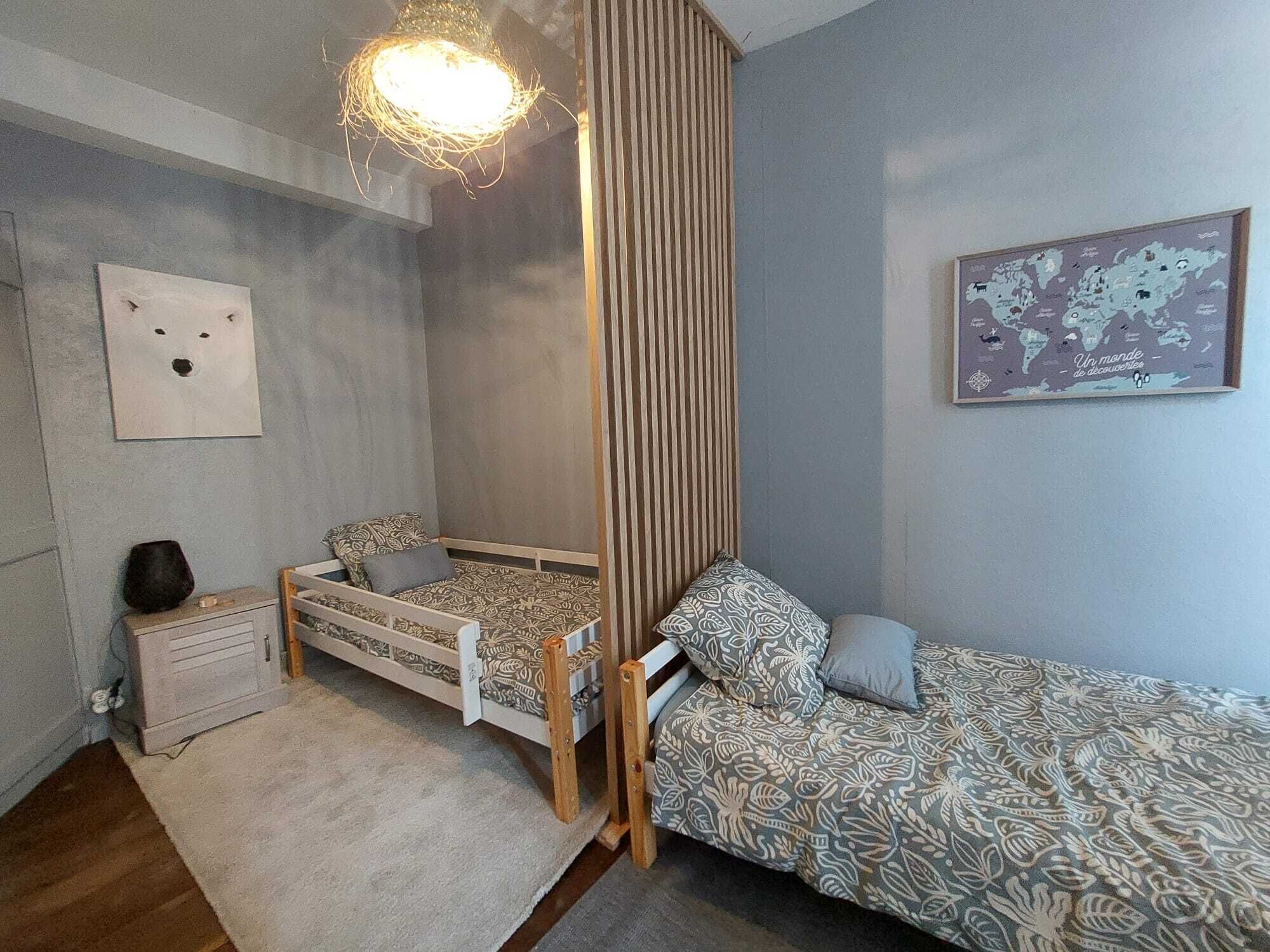 A child's bedroom with a bunk bed, a small bedside table, a world map on the wall, and a unique hanging light fixture.