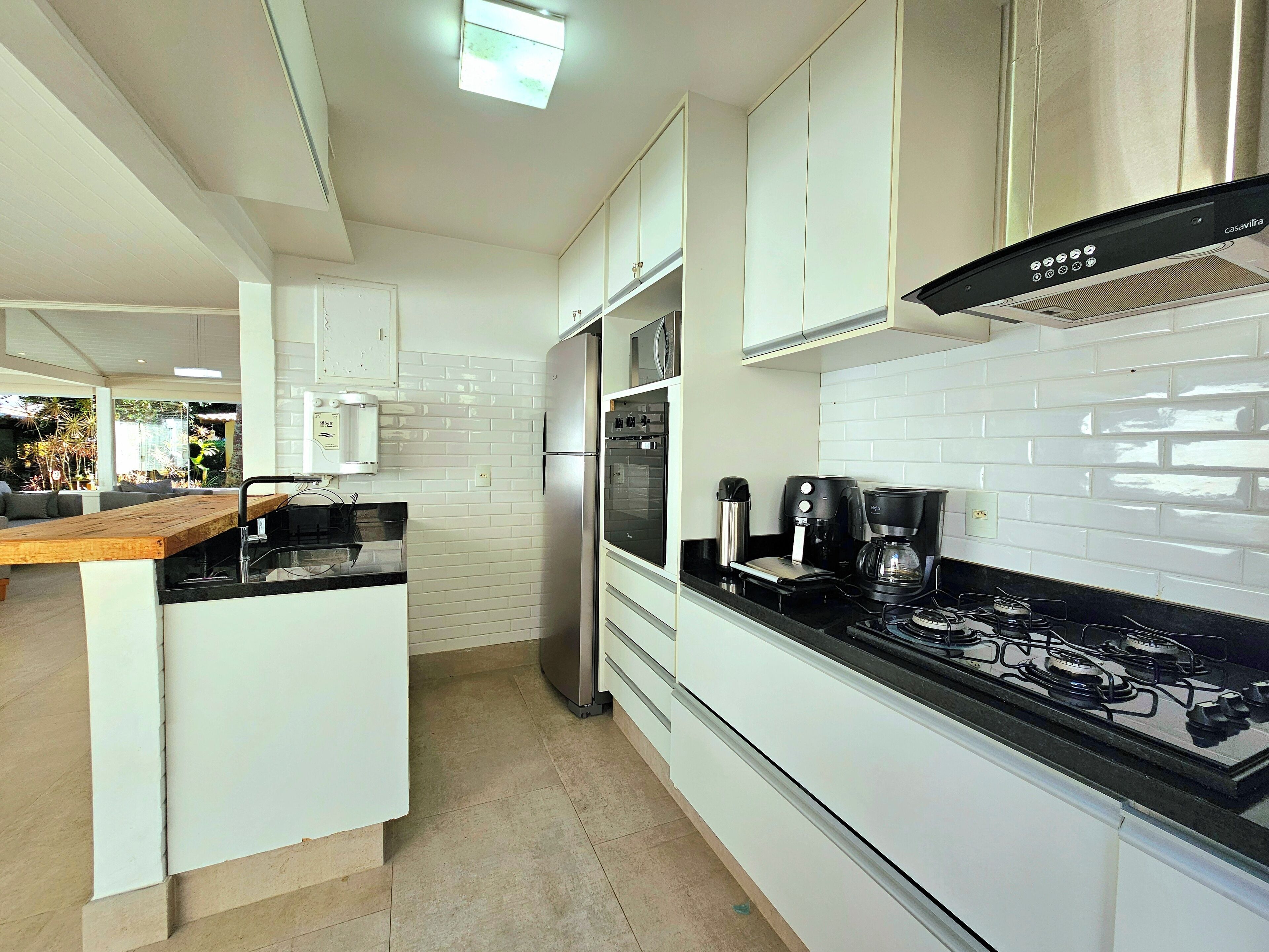 A modern kitchen with white cabinetry, a stainless steel refrigerator, a gas stove, and a coffee maker.