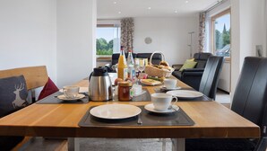 A dining area with a wooden table set for breakfast, including plates, cups, and a coffee pot.