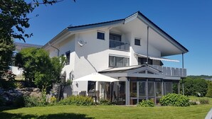 A two-story house with a balcony, a covered patio, and a well-maintained garden.
