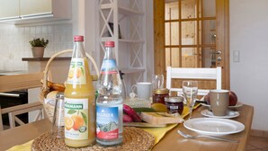 A breakfast table with orange juice, water, bread, and fruits.