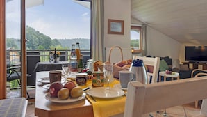 A dining area with a table set for breakfast, a view of the outdoors, and a television in the background.