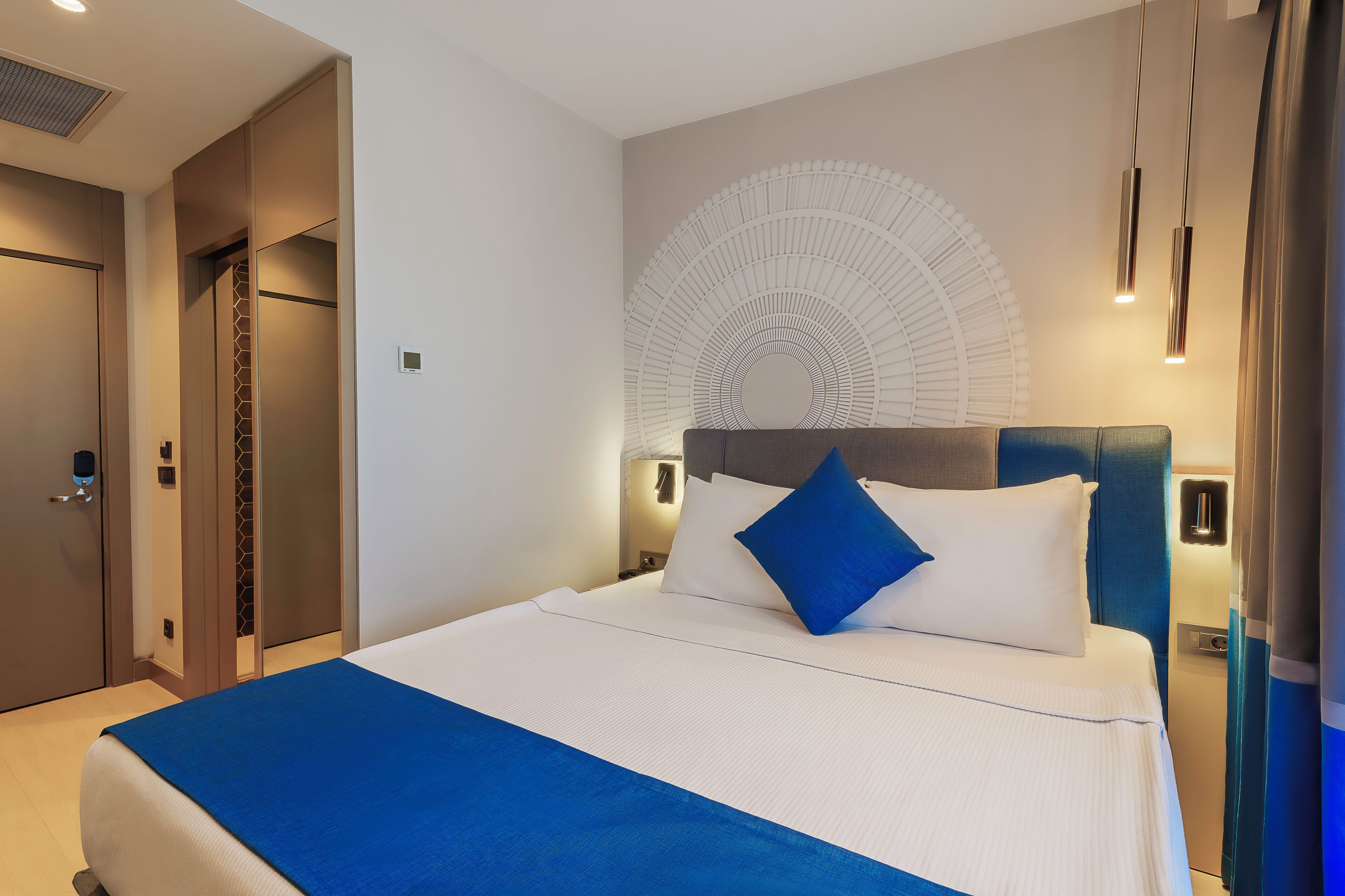 Una habitación de hotel con cama, cabecera, una obra de arte en la pared y una mesita de noche.