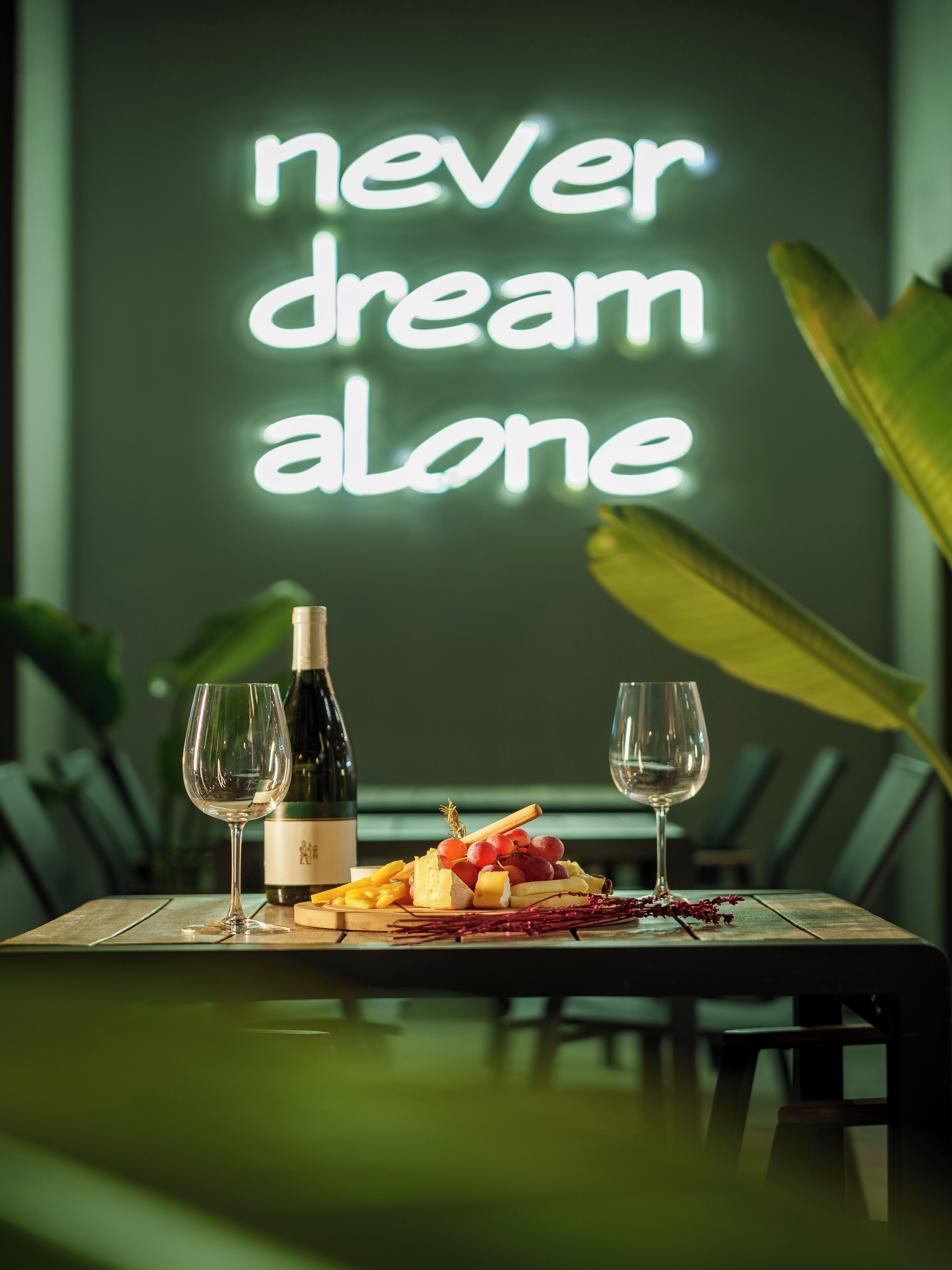 A table with a bottle of wine, glasses, and a cheese platter.