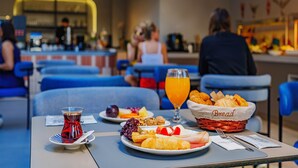 Een ontbijtruimte met tafels gedekt, inclusief borden met eten, brood en een glas sinaasappelsap.