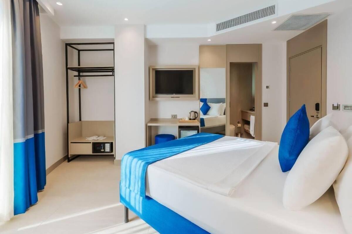 A hotel room with a bed, a desk, a TV, a wardrobe, and a bathroom.