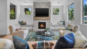 A modern living room with a stone fireplace, comfortable seating, and large windows. - Bluebird Day - Westside Retreat, Discover luxury at a spacious 4-bedroom home in Bend, OR. (Bend)
