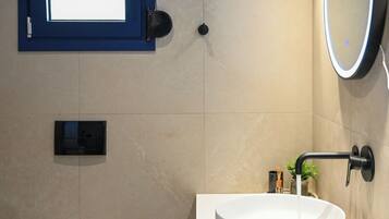Une salle de bain moderne équipée de toilettes, d’un bidet, d’un lavabo et d’un miroir.