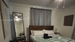 A bedroom with a wooden bed, a bedside table, a mirror, and a ceiling fan. - 2:1 Bunkroom Bungalow (Greenville)