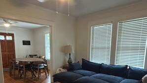 A living room with a sofa, a coffee table, a dining table with chairs, and a ceiling fan. - 2:1 Bunkroom Bungalow (Greenville)