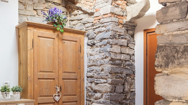 A stone wall, wooden door, and a table with chairs and a fruit bowl. - T-Rooftop (Como)