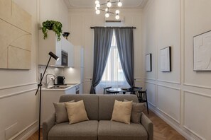 A living room with a sofa, a coffee table, a dining table, and a chandelier.