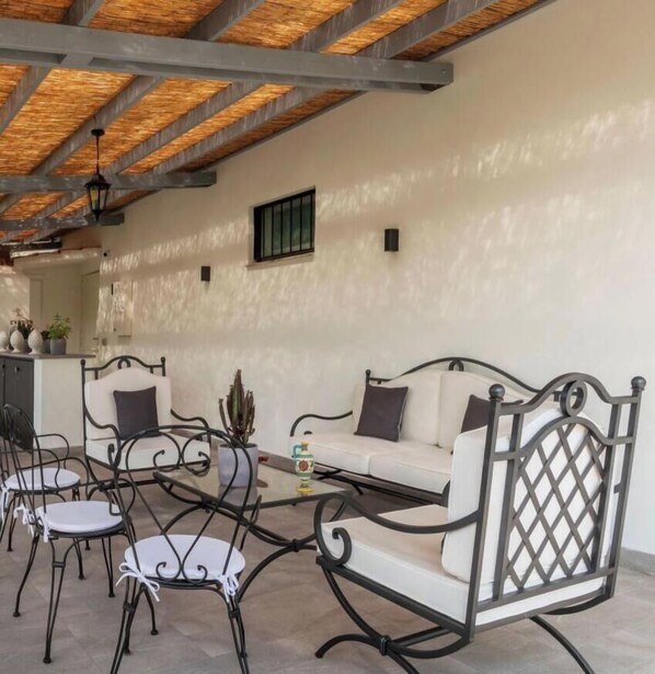An outdoor seating area with a sofa and chairs, a table, and a potted plant.