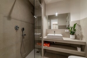 Ein modernes Badezimmer mit Duschkabine aus Glas, einem weißen Waschbecken und einem Spiegel darüber.