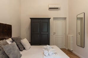 A bedroom with a bed, dark wardrobe, white door, and a mirror on the wall.