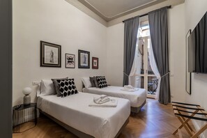 Een hotelkamer met twee bedden, een tafeltje, een televisie en een raam met gordijnen.