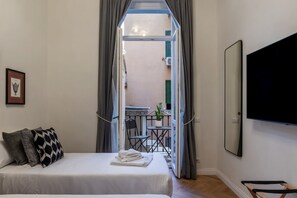 A bedroom with a bed, a TV, and a balcony with a table and chairs. - Castro Pretorio 9 - FromHometoRome (Roma)