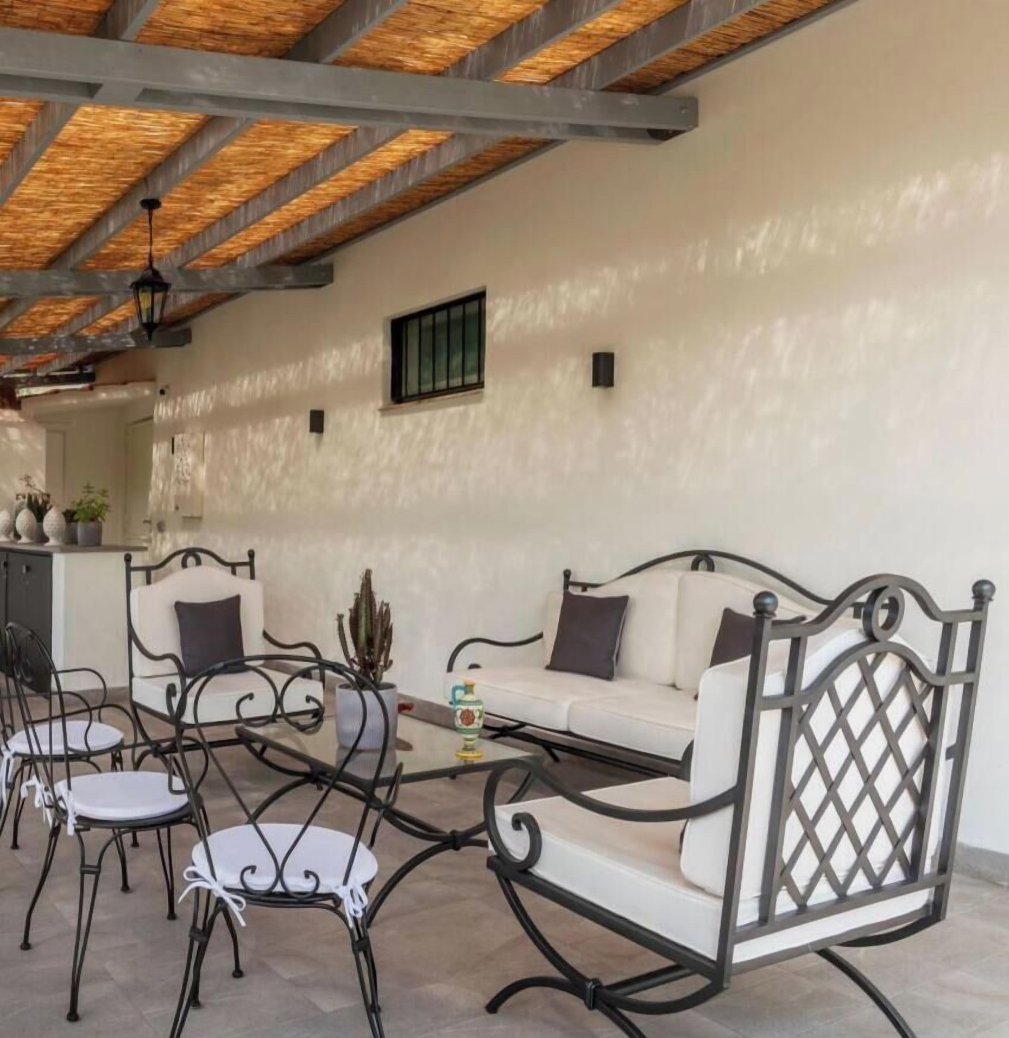 Un espacio al aire libre con sillones y sillas, una mesa y una planta en maceta.