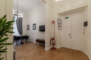 A hotel room with a dining area, a television, a fire extinguisher, and a door with an emergency exit sign. - Castro Pretorio 9 - FromHometoRome (Roma)