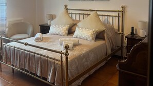 A neatly arranged bedroom with a bed, bedside tables, a chair, and a hanging light fixture. - Charming B&B (San Ciro - Ulmi - Filci)