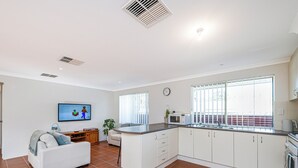 A modern kitchen with white cabinets, a built-in microwave, and a large window. - Beauty And the Beach - Coastal Comfort at its best. (Guilderton)