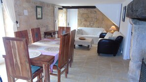 Un coin repas avec une table et des chaises en bois, un canapé blanc et un mur en pierre.