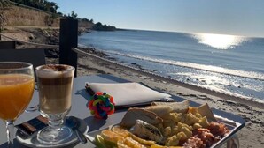 A breakfast setup on a beach with a view of the ocean, including a plate of food, a glass of orange juice, and a cup of coffee. - La sunrise sea view and golf luxury apartment (los alcazares)