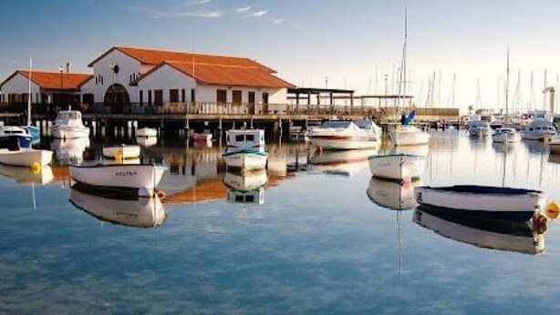 A marina with several boats docked, a building with a red roof, and calm water. - La sunrise sea view and golf luxury apartment (los alcazares)