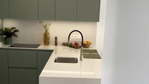 A modern kitchen with a white countertop, a sink, and green cabinets. - La sunrise sea view and golf luxury apartment (los alcazares)